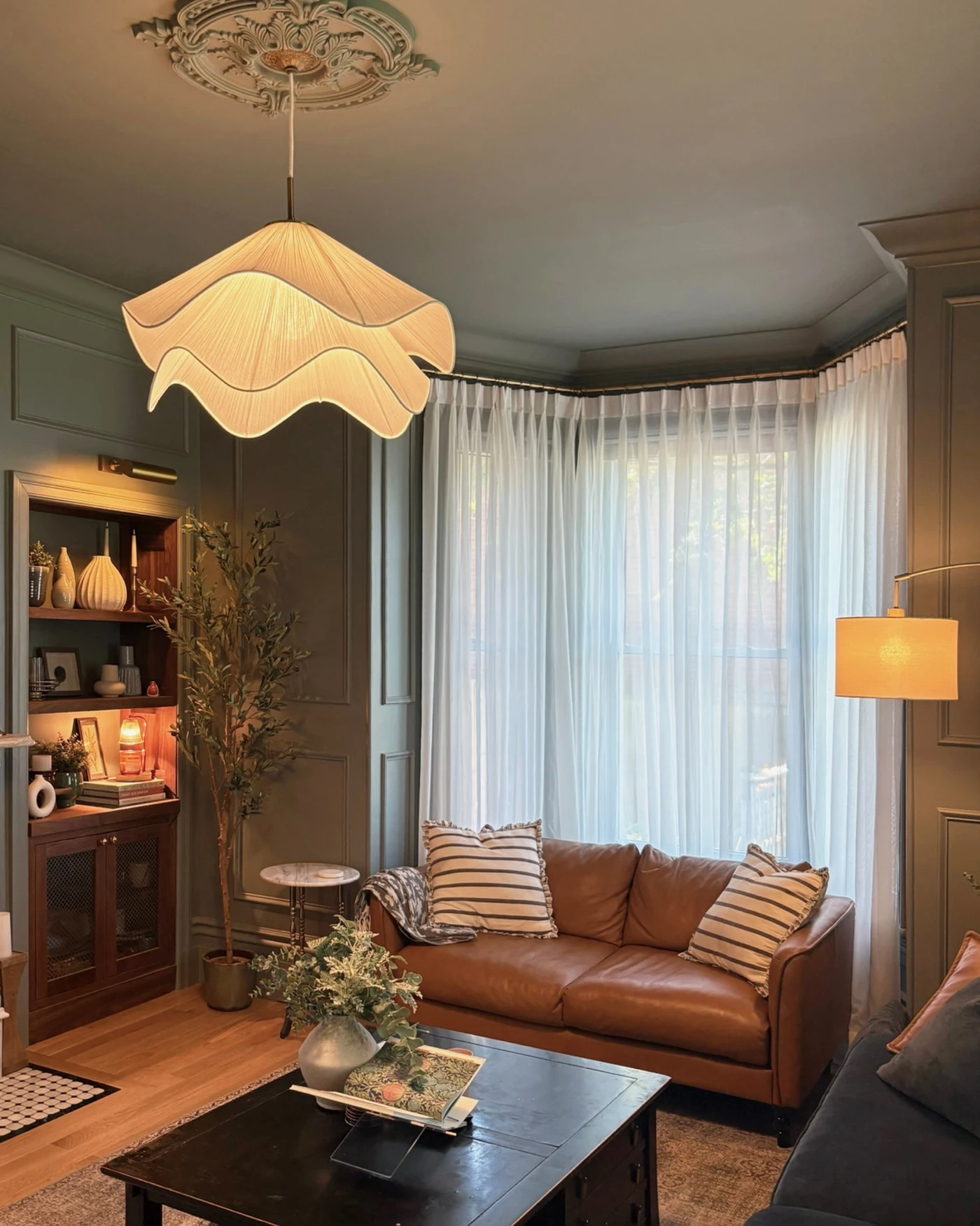 Collected living room with historic fireplace, sculptural pendant, built-in shelving, and layered furnishings